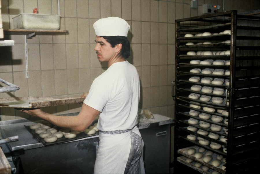 trabajador de una panadería metiendo una bandeja en el horno