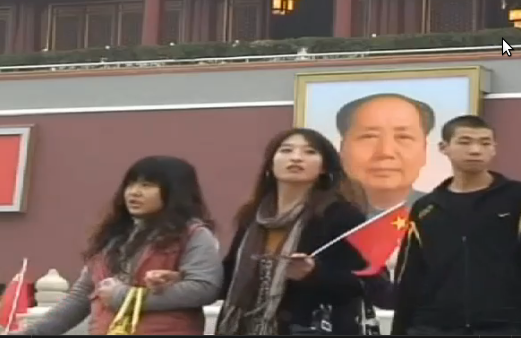 Unas chicas muy modernas pasan ante un edificio con la foto de Mao Zedong