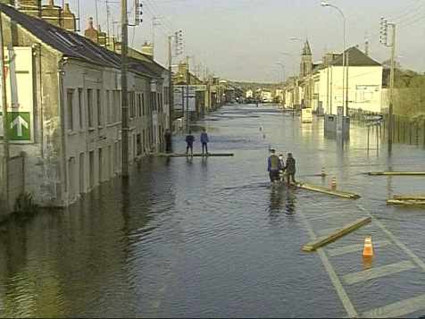 unas personas caminan por una calle completamente inundada