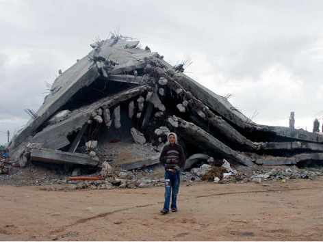 un joven ante una casa completamente destruída