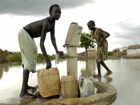 Un chico y una chica sacan agua del pozo, todo el terreno está inundado