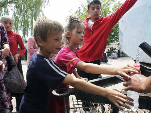 unos niños llenan una botella de agua de un depósito