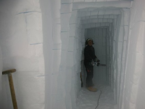 Un enorme túnel de hielo, al fondo una investigadora con una sierra mecánica