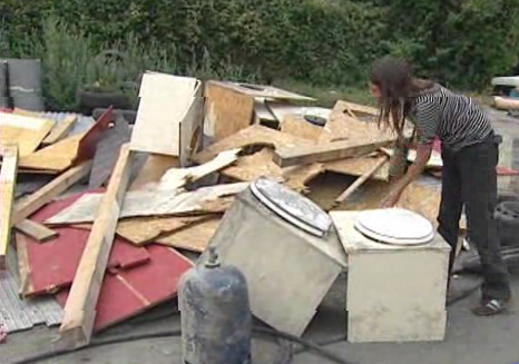 una chica rebusca entre los restos del campamento