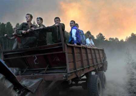 Un grupo de voluntarios en un camión, al fondo se ve el incendio