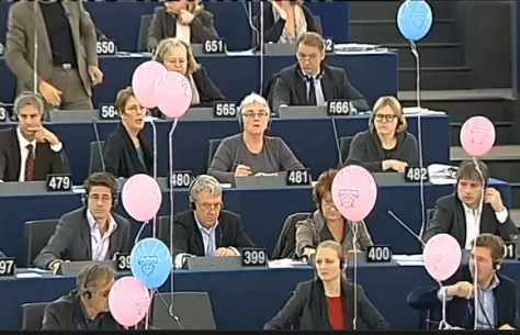 eurodiputados en sus escaños con globos rosa y azules con el dibujo de un bebé