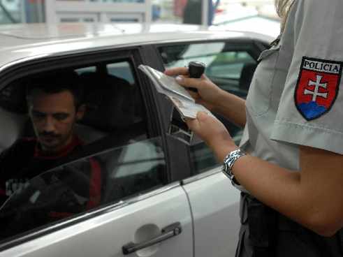 Una policía mira el pasaporte de un hombre que está dentro de un coche