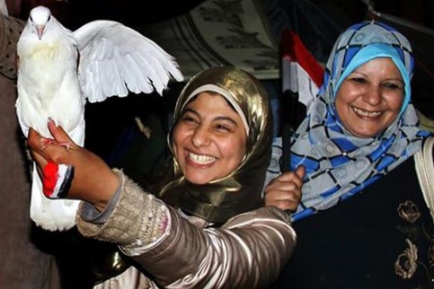 dos mujeres con una paloma blanca en las manos felices tras la marcha de Mubarak