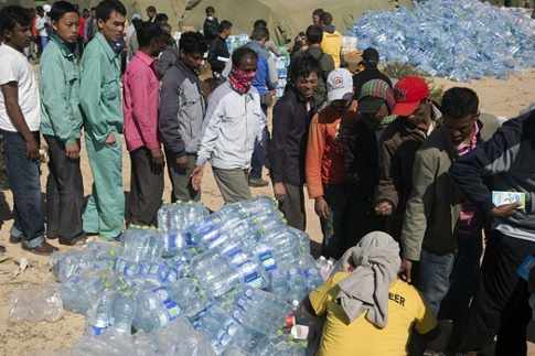 Un fila de refugiados entre grandes montones de botellas de plástico