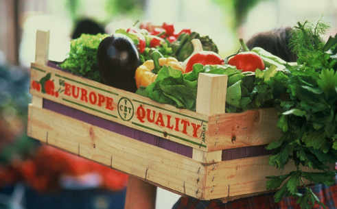 Un hombre lleva una caja con verduras