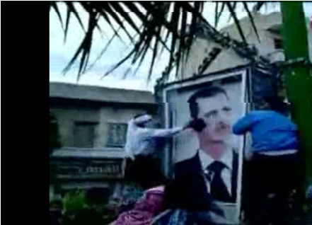 Manifestantes destrozan una foto de Bashar el Assad