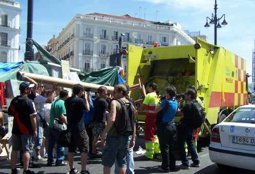 Los acampados llevan cosas a un camión de la basura