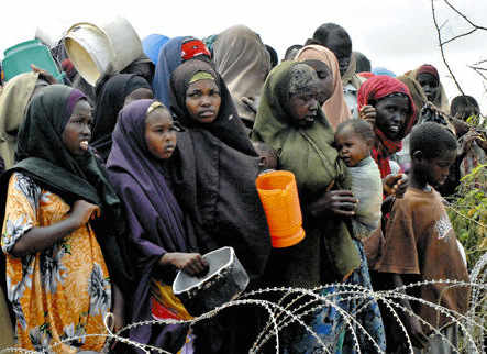 Un grupo de mujeres tras una alambrada esperando comida